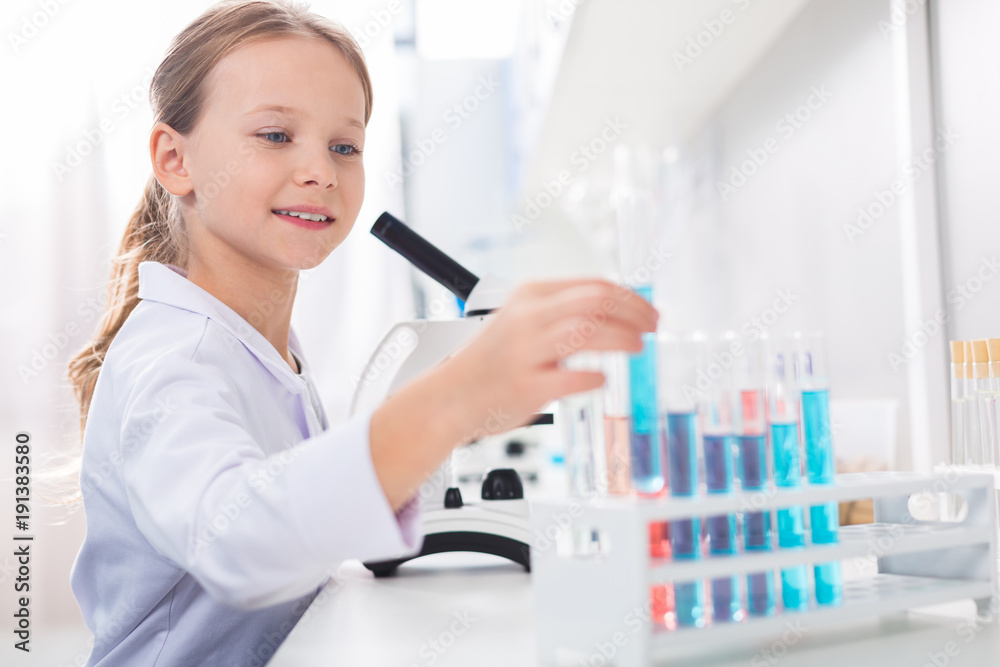Charming enthusiastic girl putting vial in stand Charming enthusiastic girl putting vial in stand