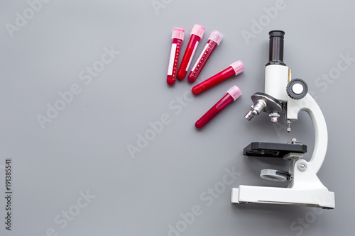 Do blood test in laboratory. Analysis. Blood samples in test tubes near microscope on grey background top view copy space