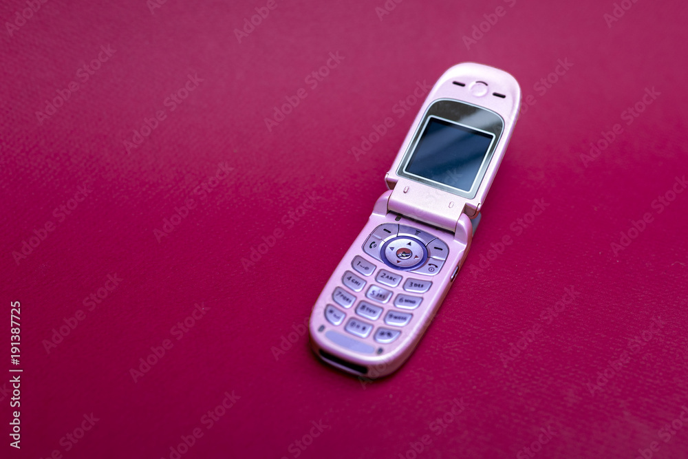 Cool and classic pink retro flip cell or mobile phone isolated against a  red background Stock Photo