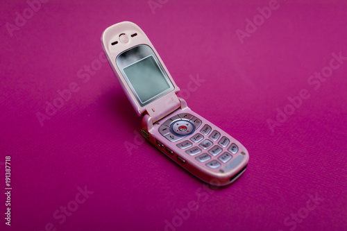 Cool and classic pink retro flip cell or mobile phone isolated against a red background
