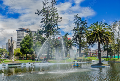 Outdoor view of lagoon in the La Alameda Park with some buildings in the background. This is the oldest park in the city of Quito