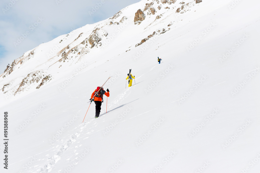 two ski freerider climbs the slope into deep snow powder with the equipment on the back fixed on the backpack.