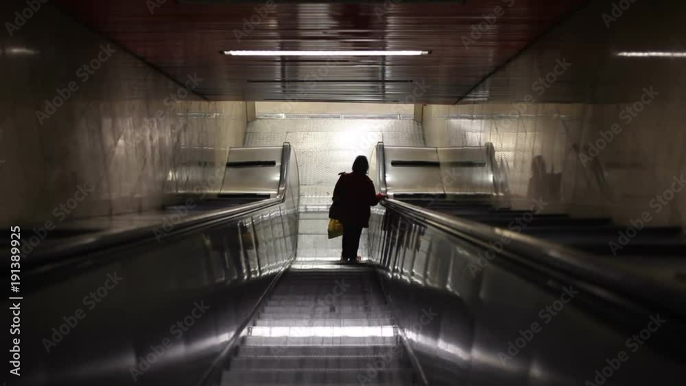 Woman riding on escalator in underground Woman riding on escalator in underground