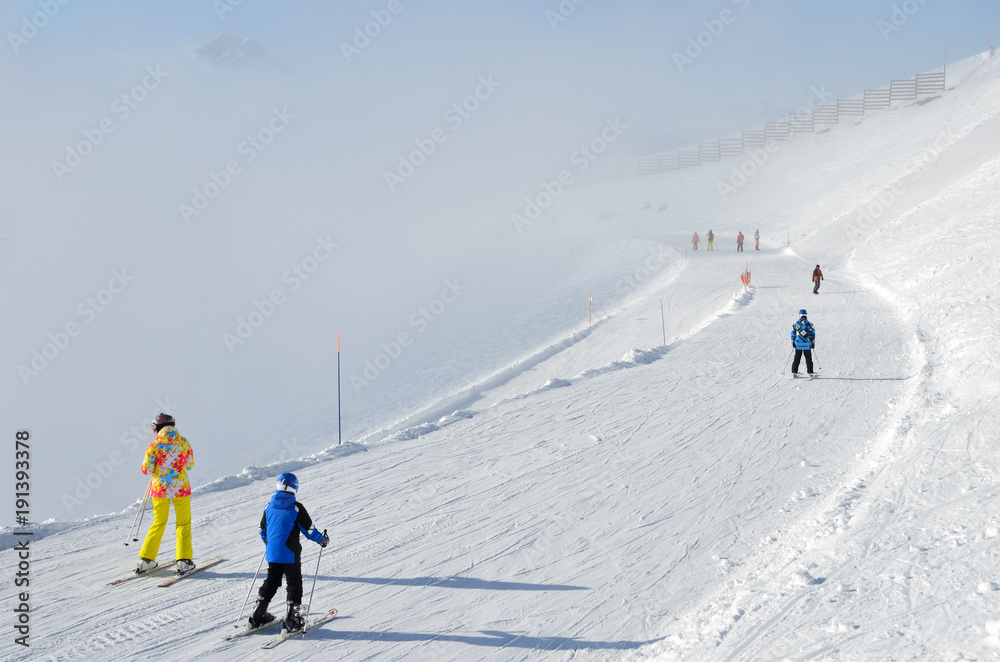 Сочи, горнолыжный курорт Роза Хутор. Лыжники в яркой спортивной одежде спускаются с горнолыжной трассы 