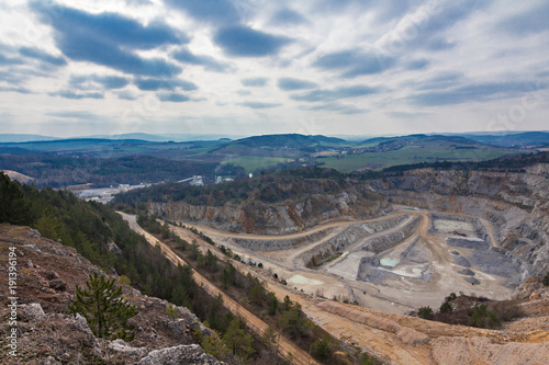 Surface mine in czech republic with forests and hills behind.