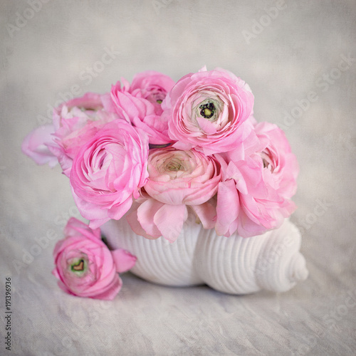 Close-up floral composition with a pink Ranunculus flowers in a shell-shaped vase.