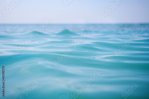 Surface of blue sea water with soft waves and clear sky on horizon. Ocean water background