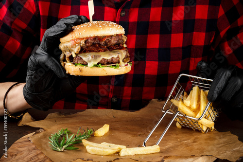 Burger with beef meat and tomato on hand in checkered shirt photo