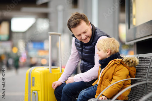 Little boy and his father waiting express train on railway station platform or waiting their flight at the airport