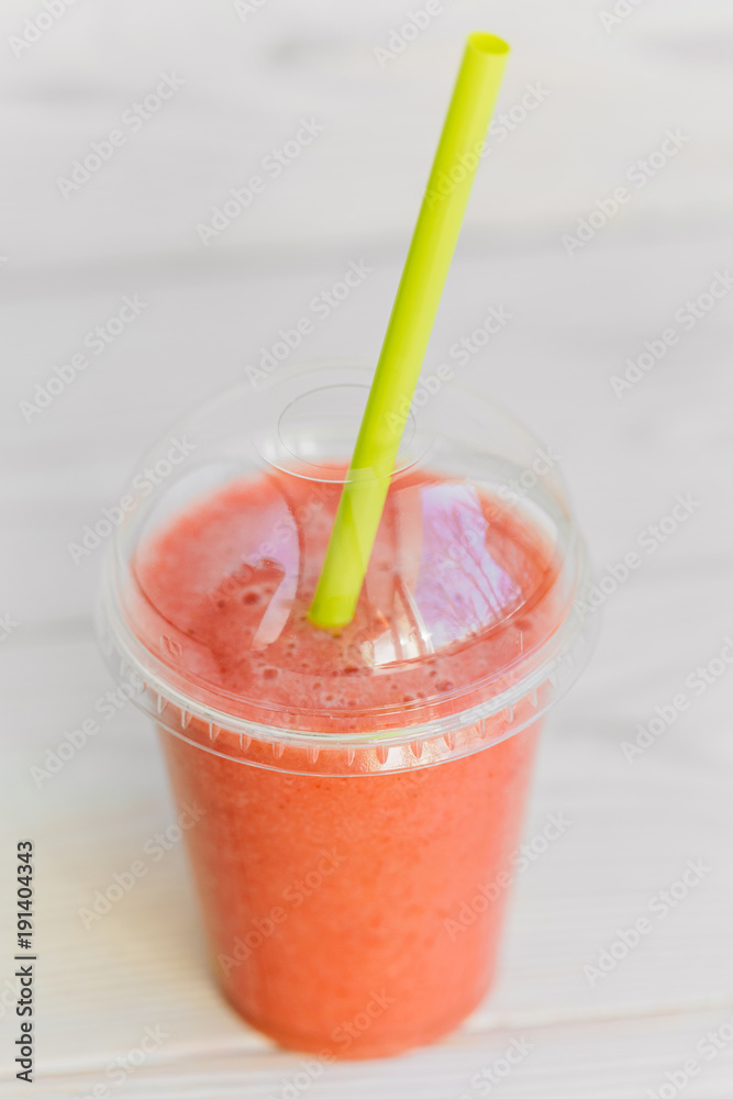 strawberry smoothie in plastic glass 2go with cocktail tube. Healthy apple banana and strawberry blended drink to go.