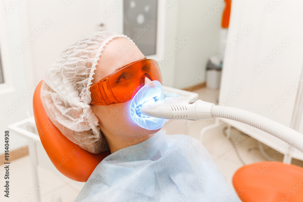 Φωτογραφία Woman patient in dental clinic whitening her teeth with UV lamp, stomatology and