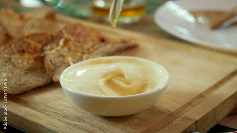 Toasts from rye bread and cheese dips into garlic sauce in bar as snack for beer party in a cheerful company of friends. Spoon mixes the sauce Toasts from rye bread and cheese dips into garlic sauce in bar as snack for beer party in a cheerful company of friends. Spoon mixes the sauce