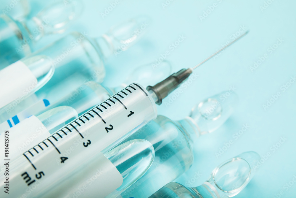 Close-up of a syringe and ampoules on a blue background. Close-up of a syringe and ampoules on a blue background.