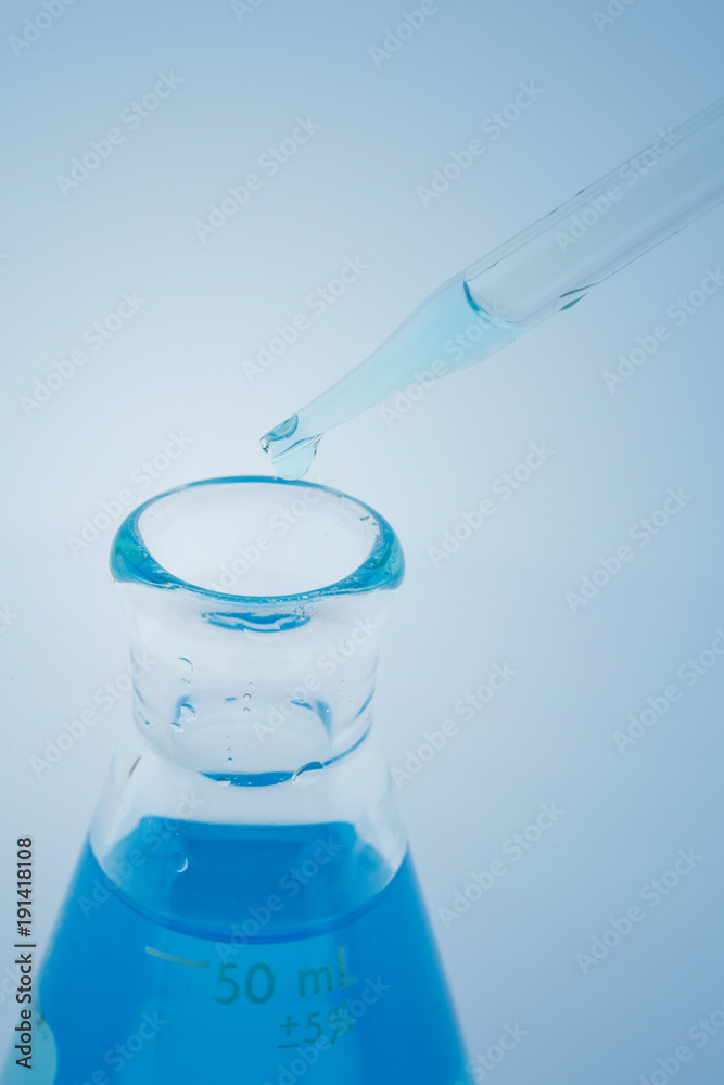 laboratory glassware with water and empty with reflection isolated on blue background laboratory glassware with water and empty with reflection isolated on blue background