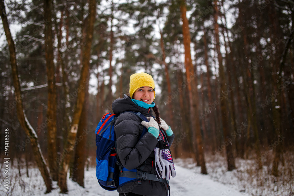 Side view of girl with backpack in winter forest