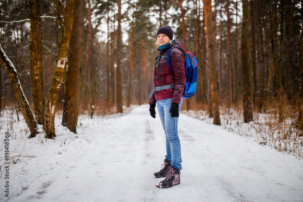 Side view of girl in hat with backpack over winter forest