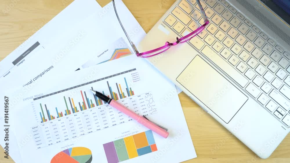 Setting up modern office desk overhead with laptop pc and graphs paperwork, overhead. Setting up modern office desk overhead with laptop pc and graphs paperwork, overhead.