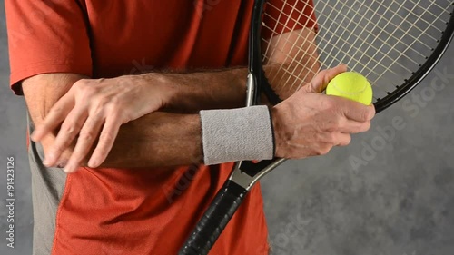 male tennis player holding racket massaging aching painful elbow 
