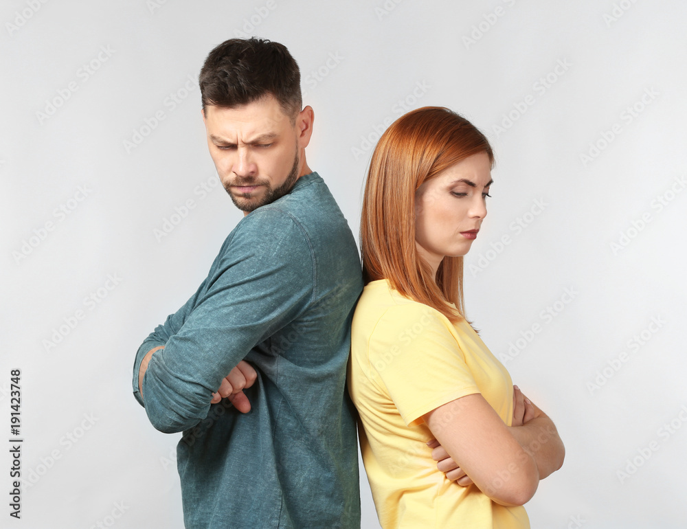 Angry couple after quarrel on light background Angry couple after quarrel on light background