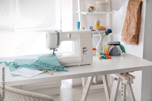 Fototapeta Naklejka Na Ścianę i Meble -  Sewing machine with fabric on table in tailor workshop