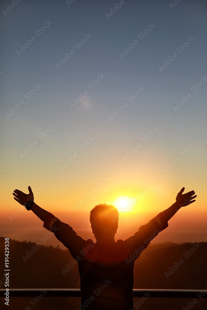 Fototapeta premium Happy Businessman show hand up for successful at beautiful sunset time, Silhouette the man hand at sunset,Silhouette of Man Raising His Hands or Open arms when sunset..