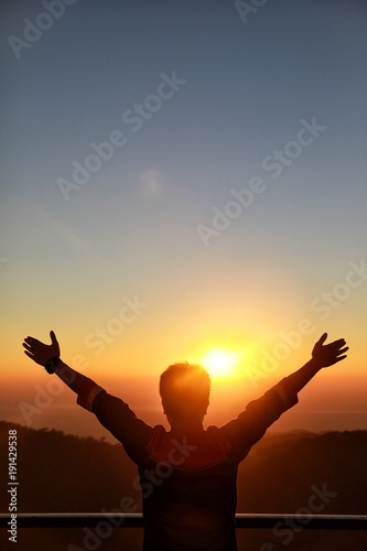 Happy Businessman show hand up for successful at beautiful sunset time, Silhouette the man hand at sunset,Silhouette of Man Raising His Hands or Open arms when sunset..