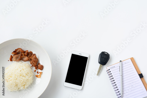 notebook with pen, car key, phone and rice on white table, top view