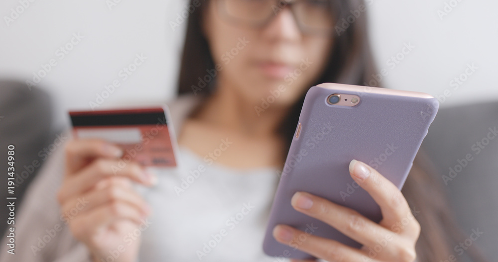 Woman shopping online with cellphone and credit card
