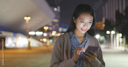 Woman check on smart phone in city at night