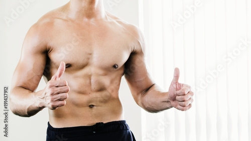 musclular body builder man stand and thumb up with white background