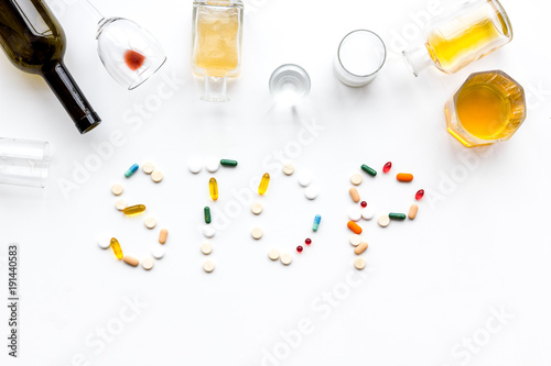 Alcoholism treatment. Glasses, bottles and pills. Word Stop on white background top view copy space