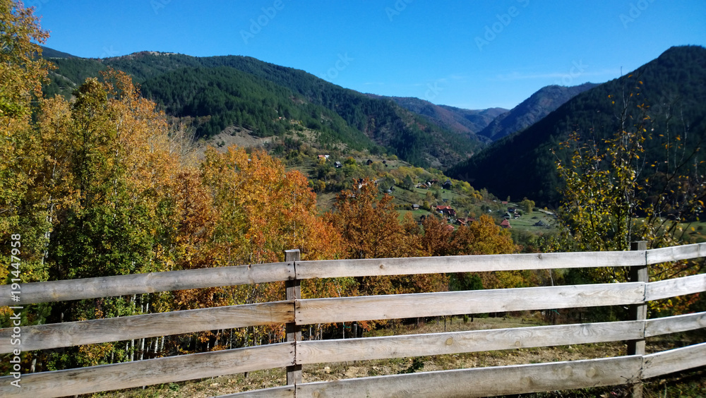 Autumn nature outside the city. A wooden fence, the tops of the mountains, colorful trees