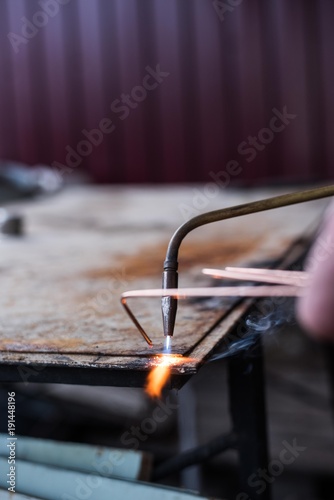 A man welds a metal with a gas burner