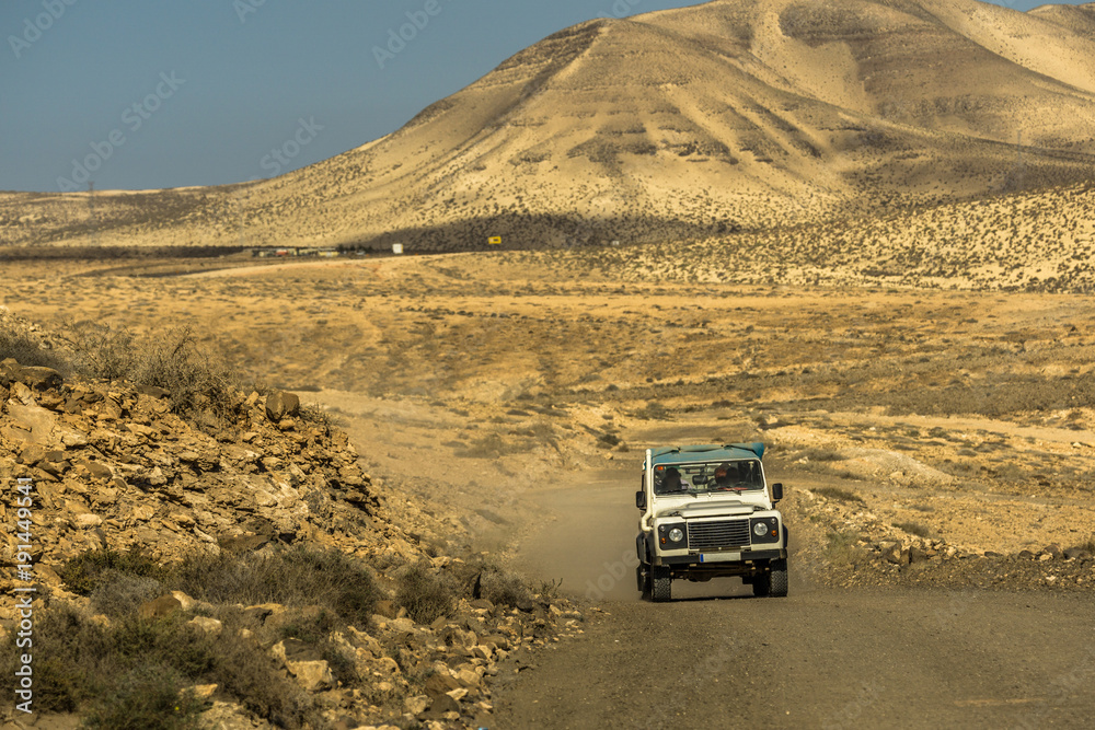 A car drives through a sand desert on Fuerteventura