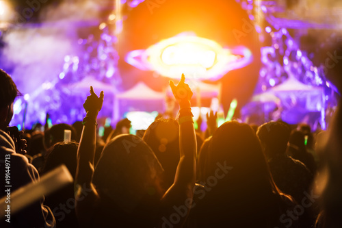 Crowd of hands up concert stage lights and people fan audience silhouette raising hands in the music festival rear view with spotlight glowing effect