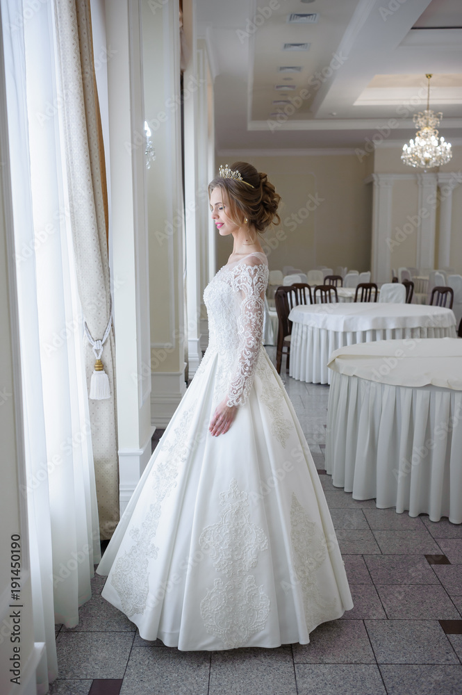 Beautiful bride in a wedding dress white interior Beautiful bride in a wedding dress white interior