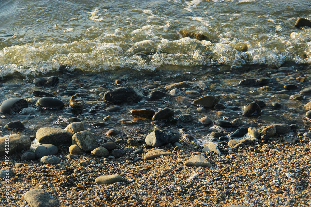 sea braking against stones, pebbles on a beach and waves background sea braking against stones, pebbles on a beach and waves background