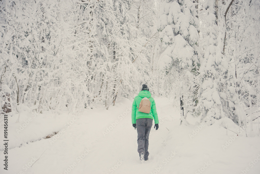 girl tourist with backpack goes through the snowy forest, the concept of a healthy lifestyle and outdoor activities in winter walks