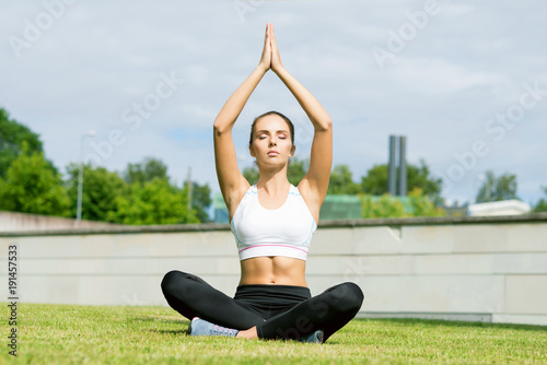 Young, fit and sporty woman doing yoga exercise meditation in the park. Fitness, sport, urban and healthy lifestyle concept.