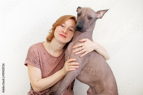 A woman hugging with a Mexican Hairless Dog on the white background