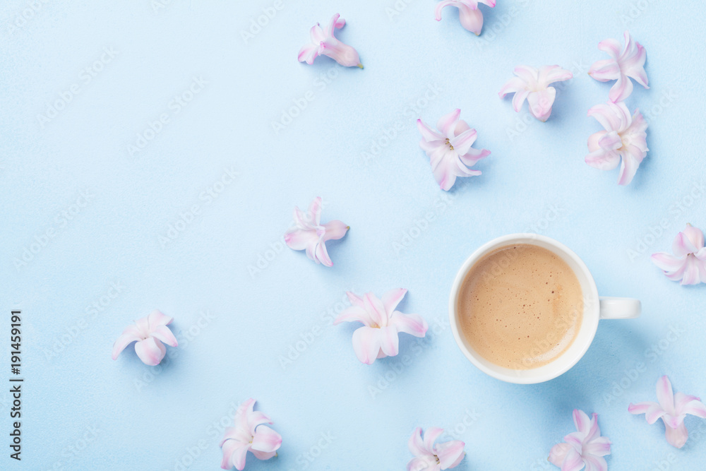 Creative composition with morning coffee and pink flowers on blue pastel background top view. Flat lay style.
