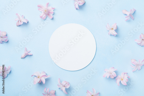 Wedding mockup with white paper list and pink flowers on blue table from above. Beautiful floral pattern. Flat lay style.