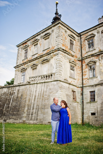 Lovely couple in love against old castle. Girl in blue dress.