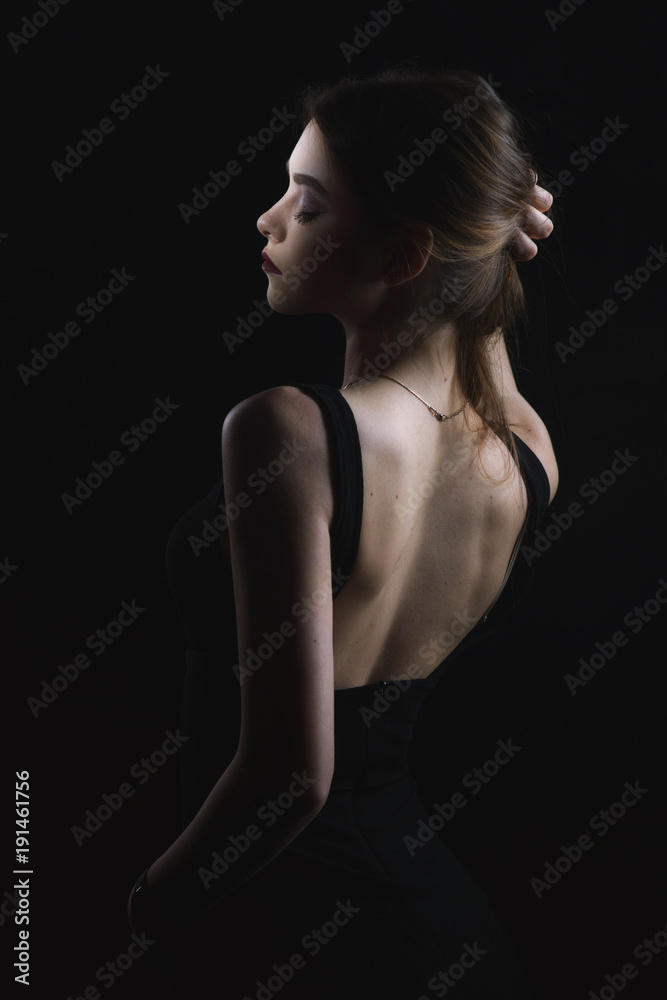 slim slim girl in dress with neckline in glamorous light from back slim slim girl in dress with neckline in glamorous light from back