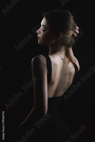  slim slim girl in dress with neckline in glamorous light from back