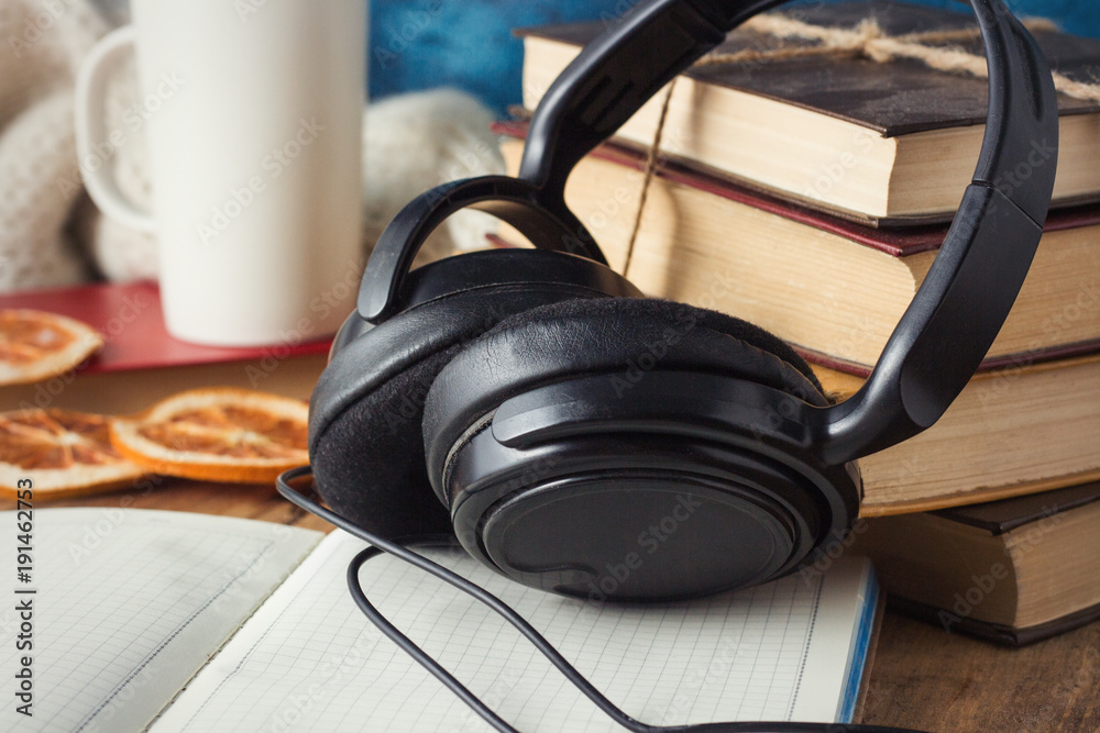 Books are stacked, Headphones, White Cup, Orange Slices, open Diary on a wooden background. The Concept of Audio Books and Audio Education Books are stacked, Headphones, White Cup, Orange Slices, open Diary on a wooden background. The Concept of Audio Books and Audio Education