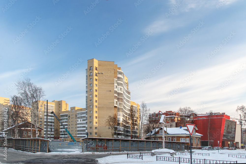 winter city landscape with wooden houses among high-rise buildings