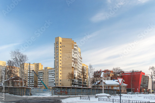 winter city landscape with wooden houses among high-rise buildings