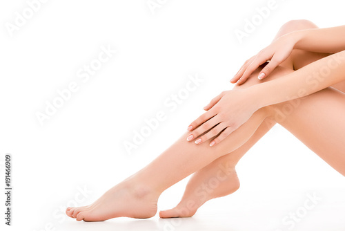 cropped view of beautiful female legs and hands, isolated on white © LIGHTFIELD STUDIOS