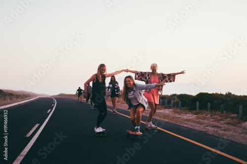 Happy group of friends riding skateboards together and having fun photo